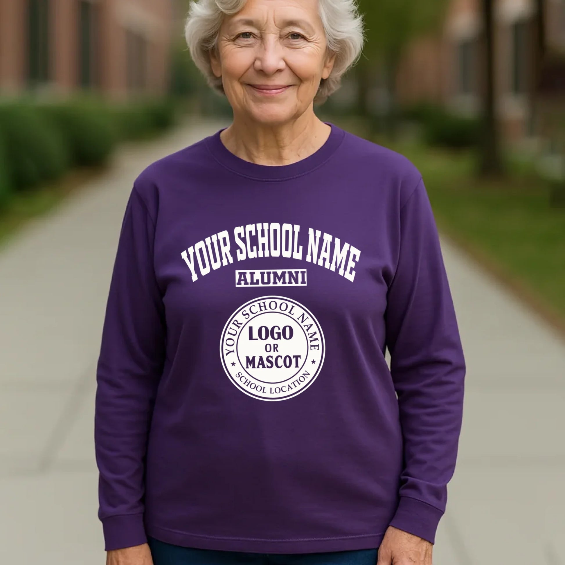 A cheerful female alumna wearing a purple personalized long sleeve shirt with her high school's classic logo.